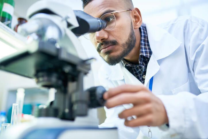 Scientist looking through a microscope in a laboratory (illustrative photo).
