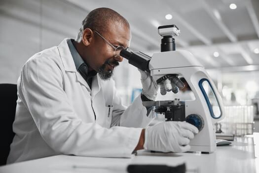 Scientist examining a sample under a microscope (illustrative photo).